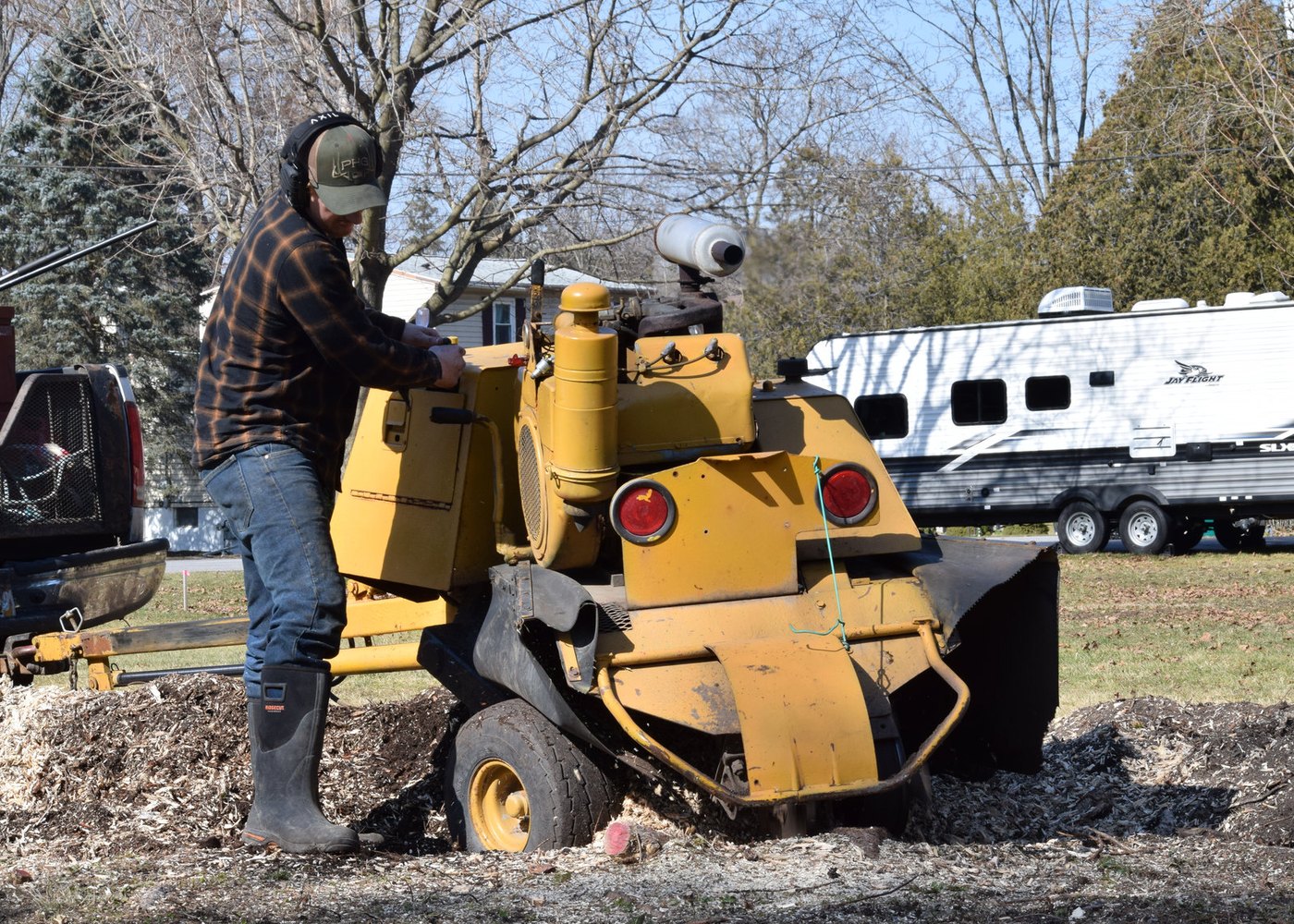 An Above and Beyond operator working a self-propelled stump grinder down into a stump